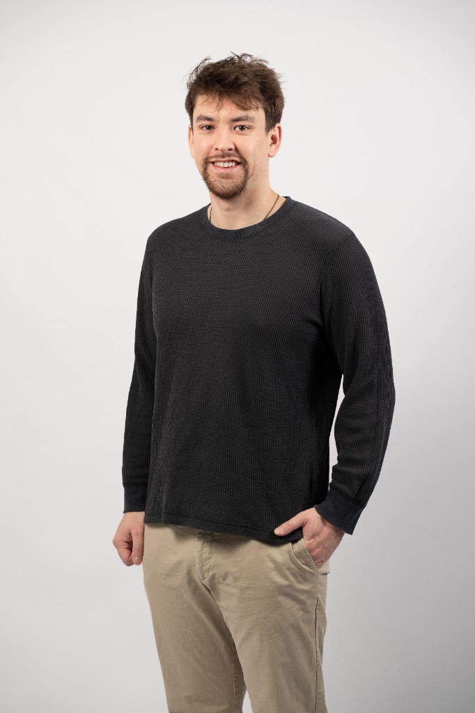 Kane, Egg Academy co-founder — portrait in a grey sweater, smiling.